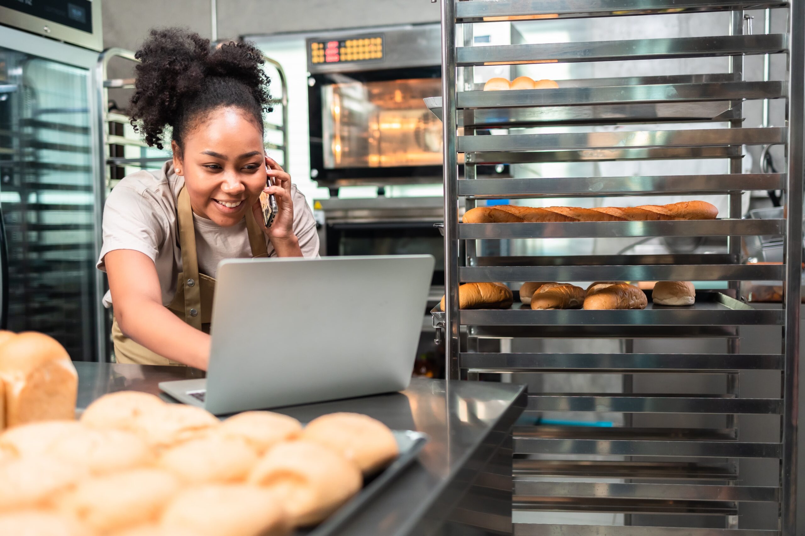 En fornøyd baker med en laptop bak i bakeriet