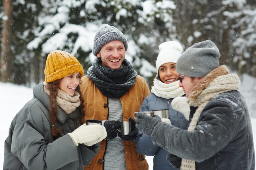 Gruppe kollegaer som nyter varm drikke sammen ute i snødekte omgivelser, som en del av vinteraktiviteter for teambuilding.