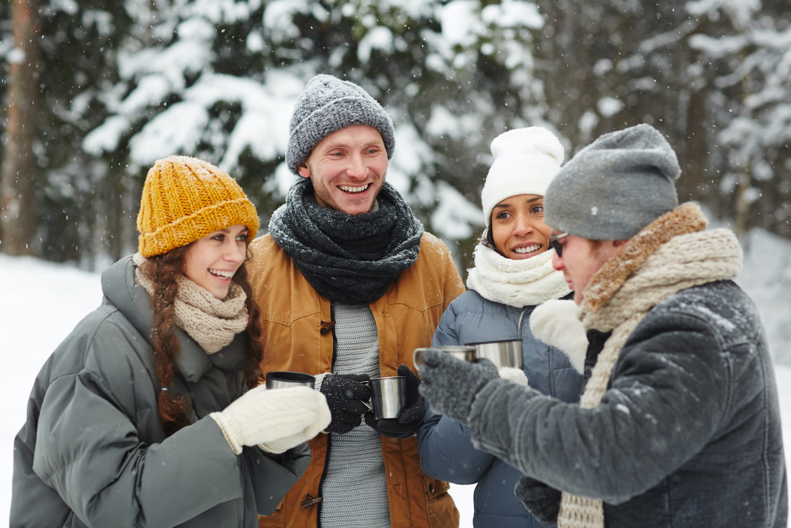 Gruppe kollegaer som nyter varm drikke sammen ute i snødekte omgivelser, som en del av vinteraktiviteter for teambuilding.