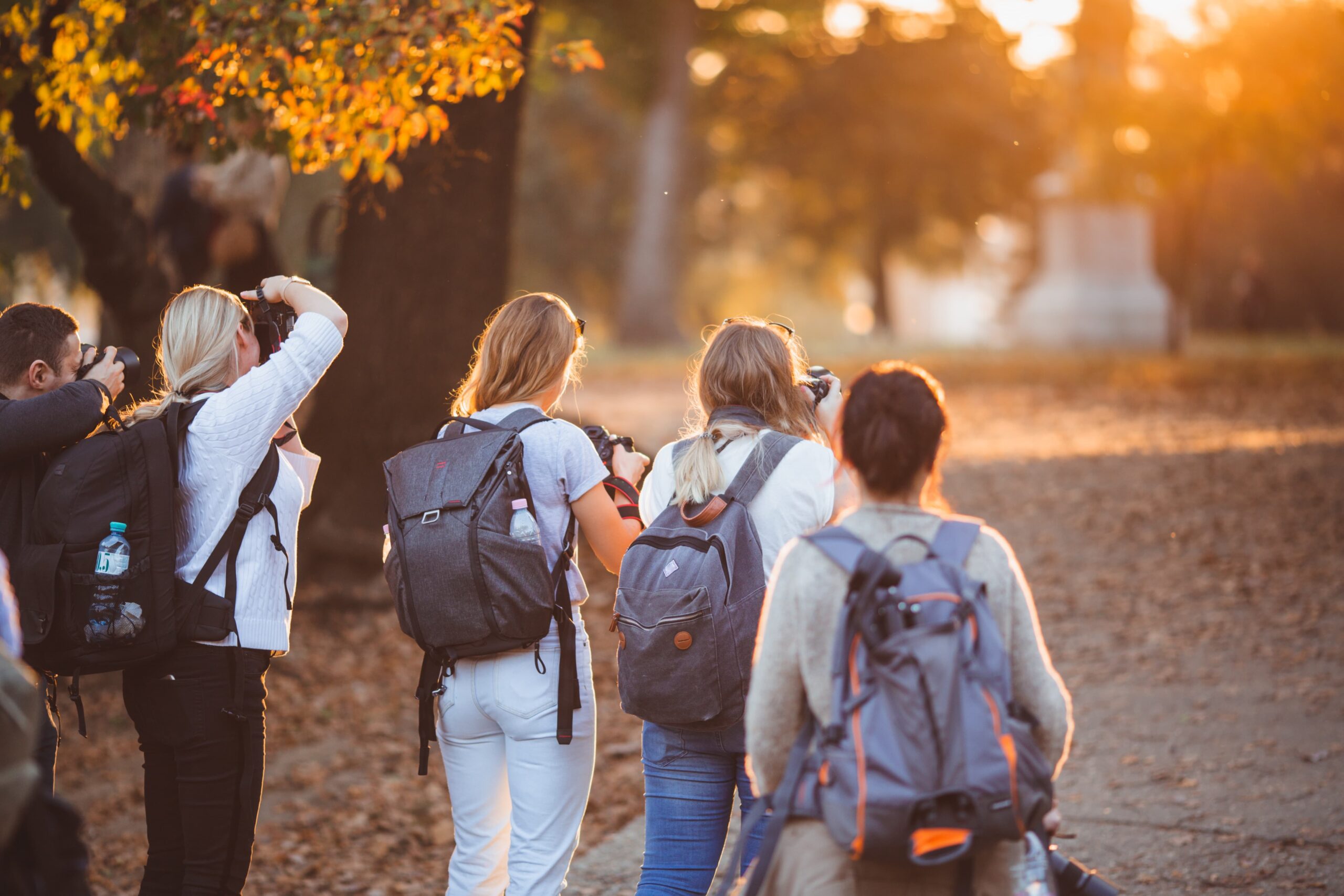 Group of people participating in outdoor photography as a drop-in activity, capturing the autumn scenery with cameras and backpacks, showcasing the flexibility and spontaneity of drop-in activities.